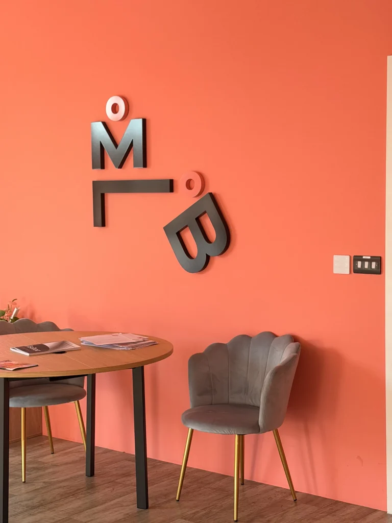 Meeting table and chairs beside the My Little Boardroom logo wall