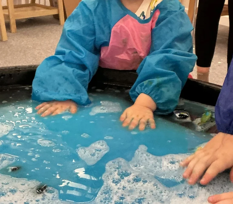Children exploring blue water during a sensory activity