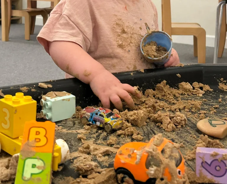 Construction toys and letter blocks in a sand activity tray