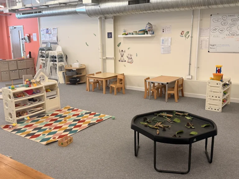 Nursery activity tables beside a colourful play rug