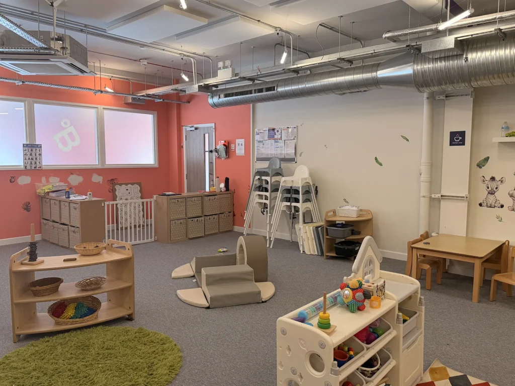 Open nursery room with toys, tables and soft play equipment