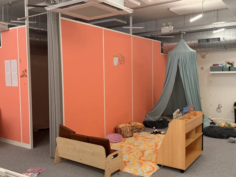 Reading nook with canopy and cushions beside a nursery partition