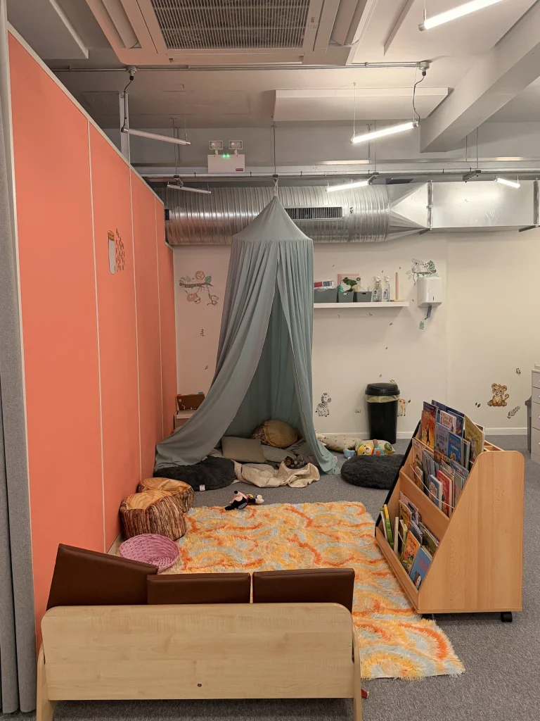 Wide view of a nursery reading nook with canopy and cushions